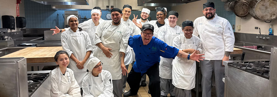 The culinary arts students and chefs posing for a photo in the kitchen.
