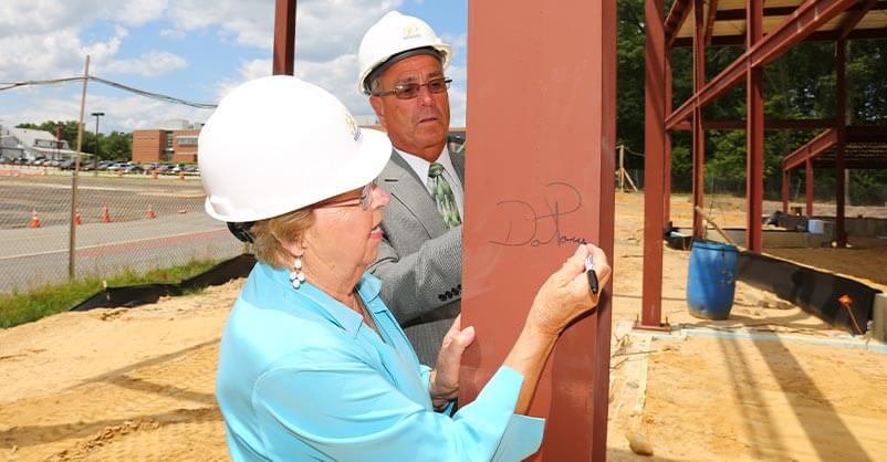 Dot Power and Ron Rios sign a beam for the new, in-construction (at the time) West Hall building.