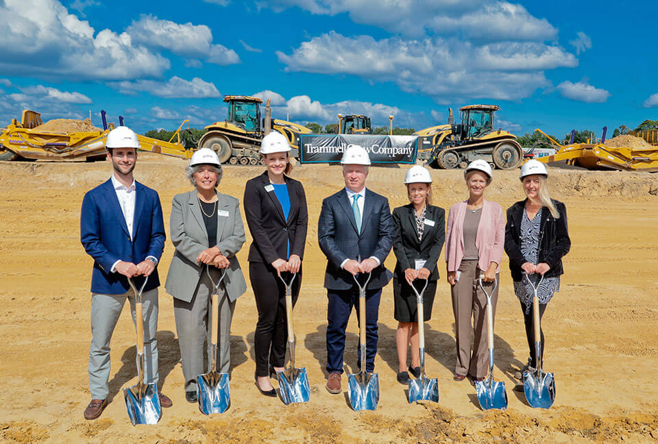 Members from Middlesex College, Trammell Crow, and the Sayreville Council line up with shovels for the Arsenal Trade Center groundbreaking. Construction equipment and a “Trammel Crow Company” banner sit in the background.