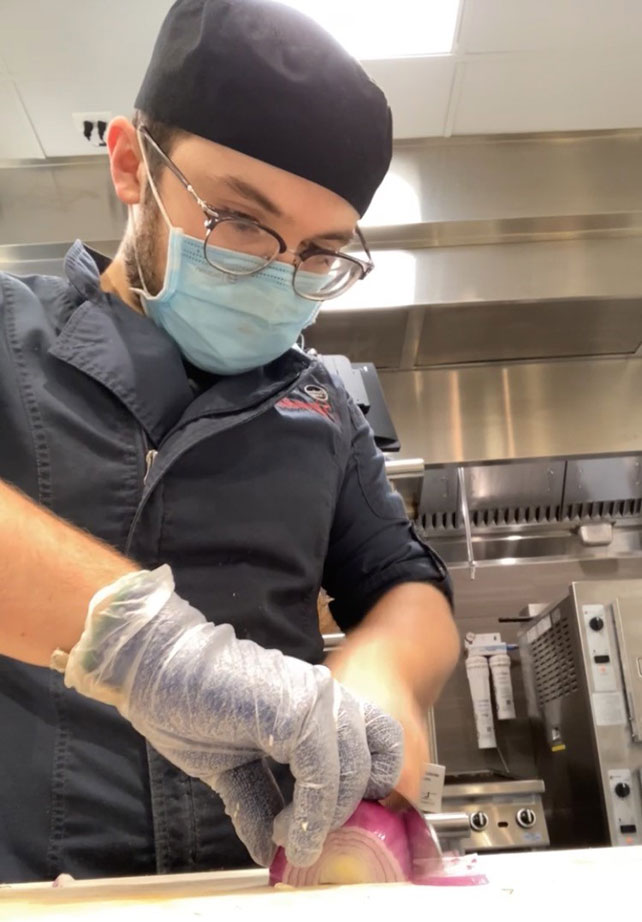 Matthew Cowan cutting an onion.