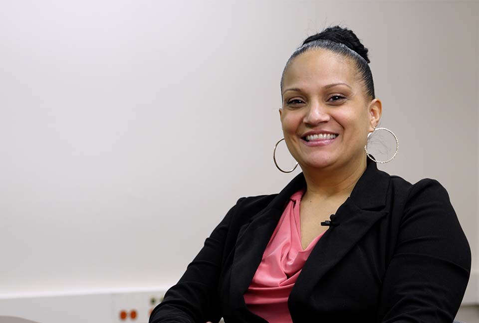 Damaris seated in an office, wearing a black blazer.