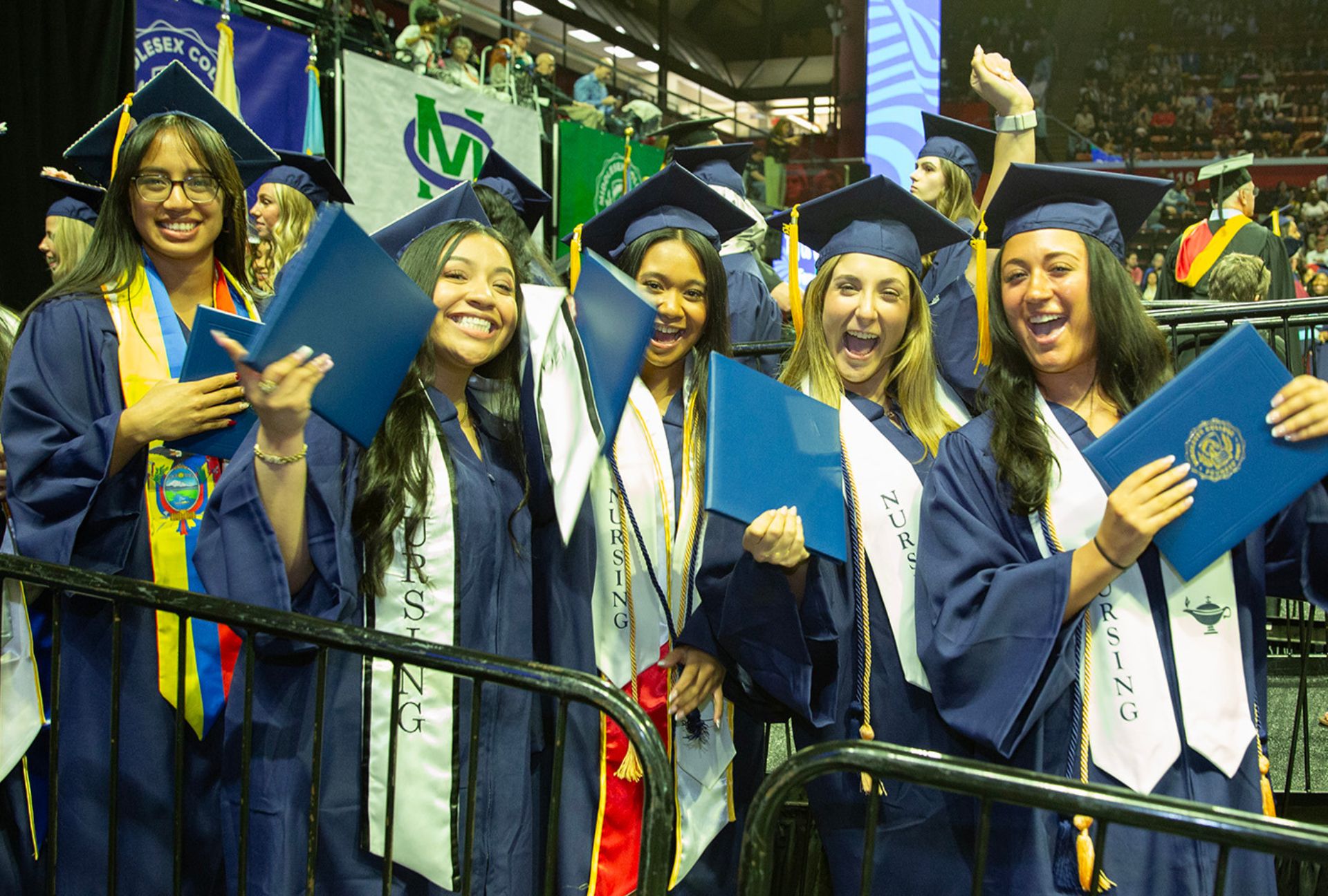 Students posing with their diplomas in hand at commencement.