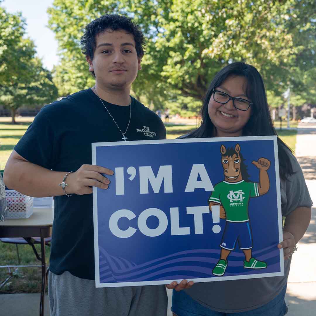 Two students hold an “I’m A Colt” sign together.