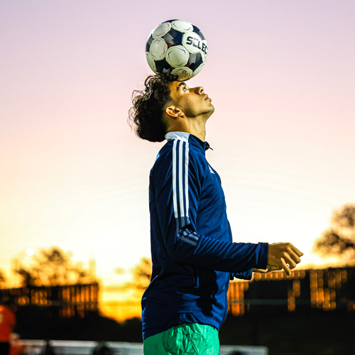 A student is effortlessly balancing a soccer ball on his head.