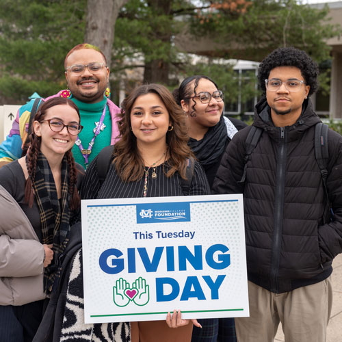 Students in the plaza holding a 'Giving Day' sign.
