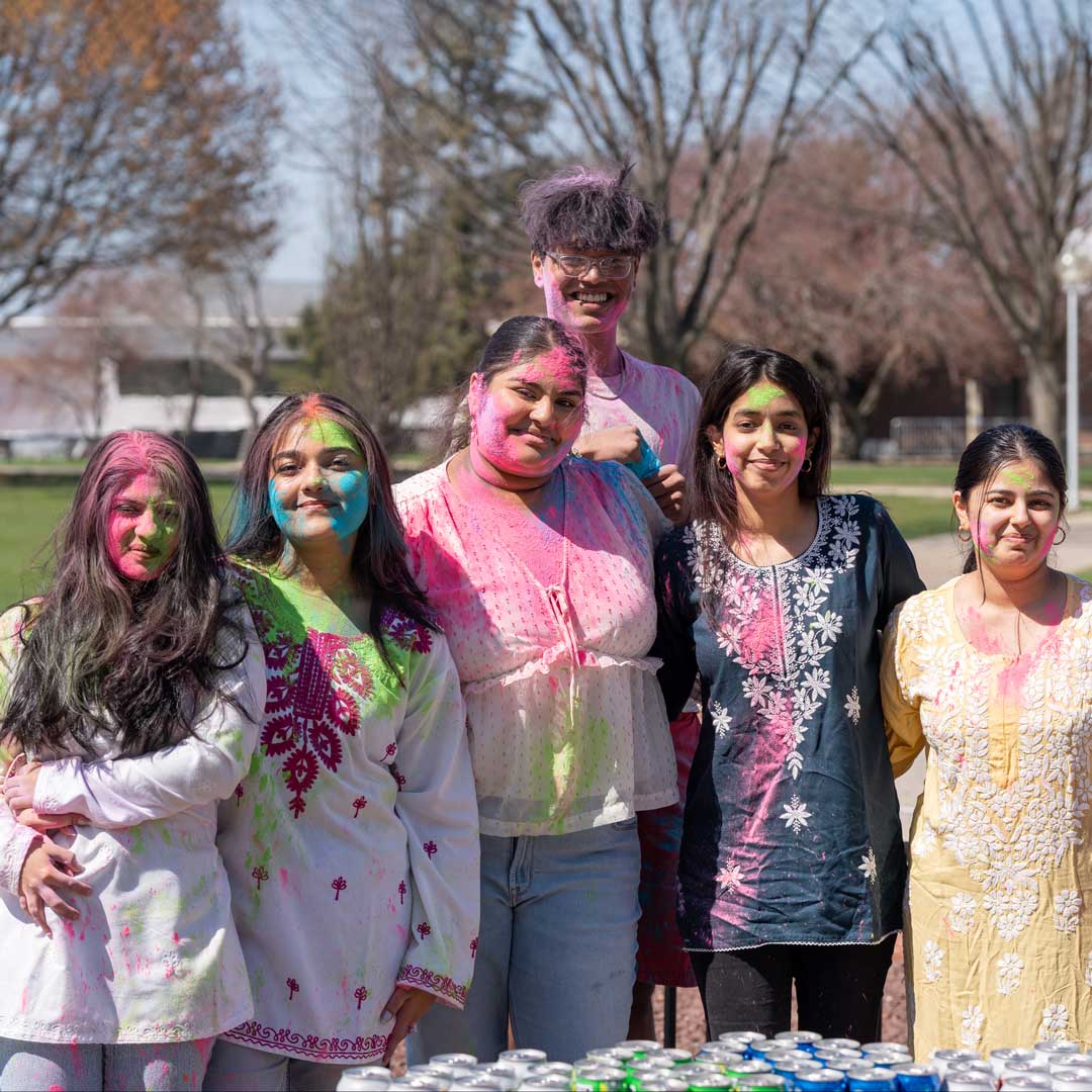 A group of students covered in dry powder colors, celebrating Holi.