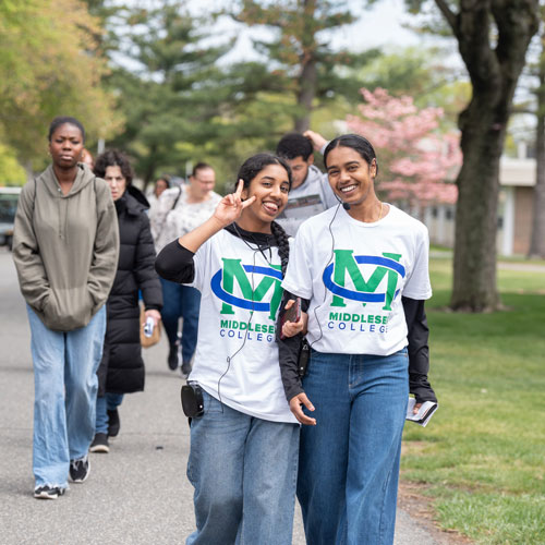 Two students posing while walking on campus.